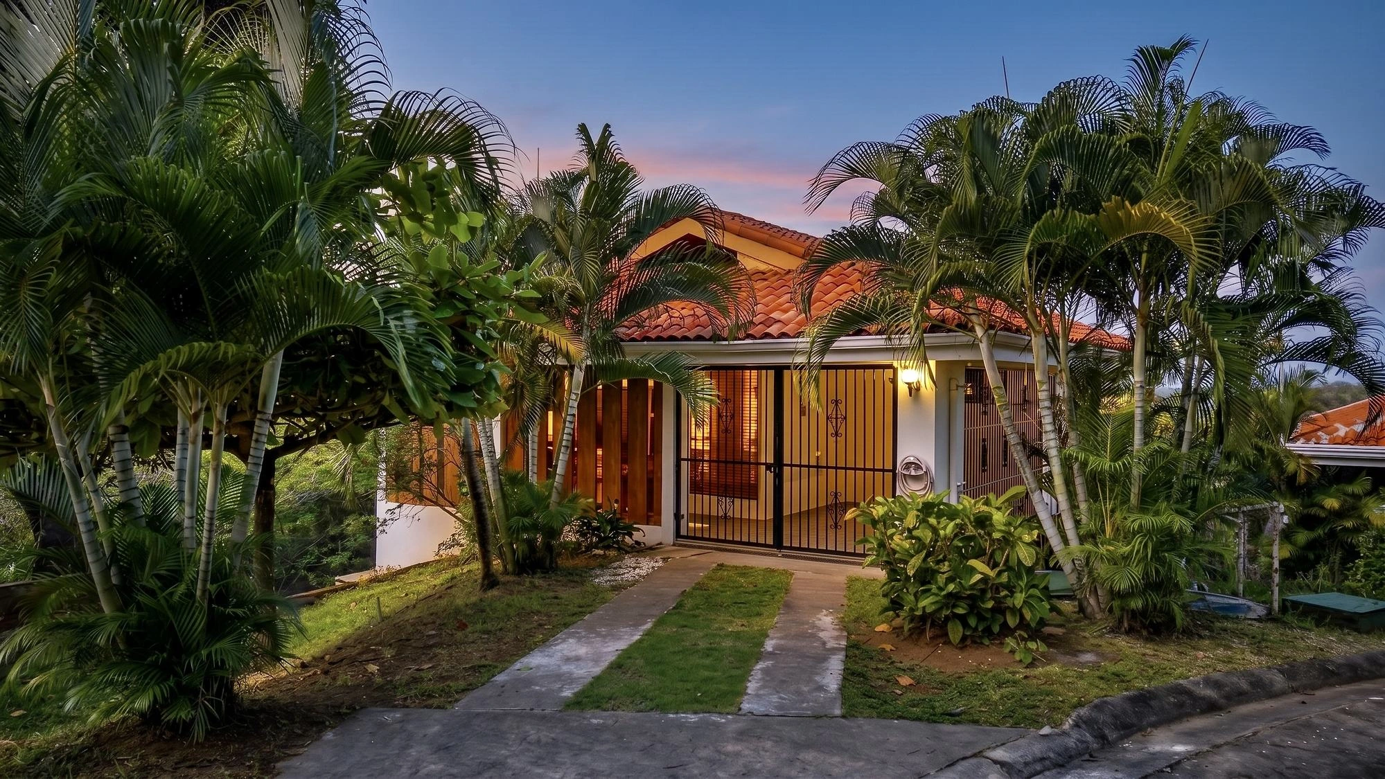 Almendros 15 entrance at dusk, framed by palms, gated and lit
