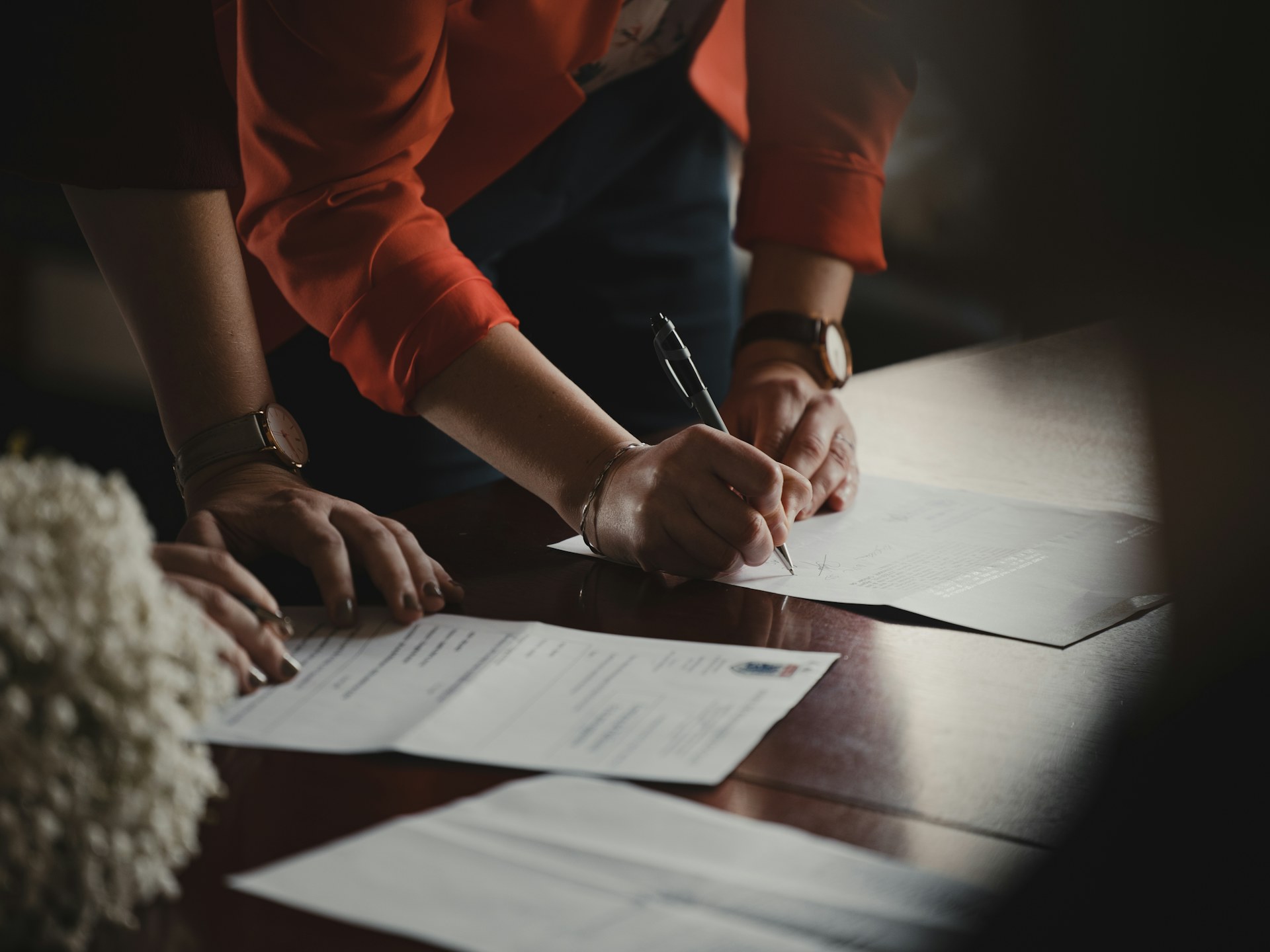 Two people reviewing and signing legal documents at a dark wooden table