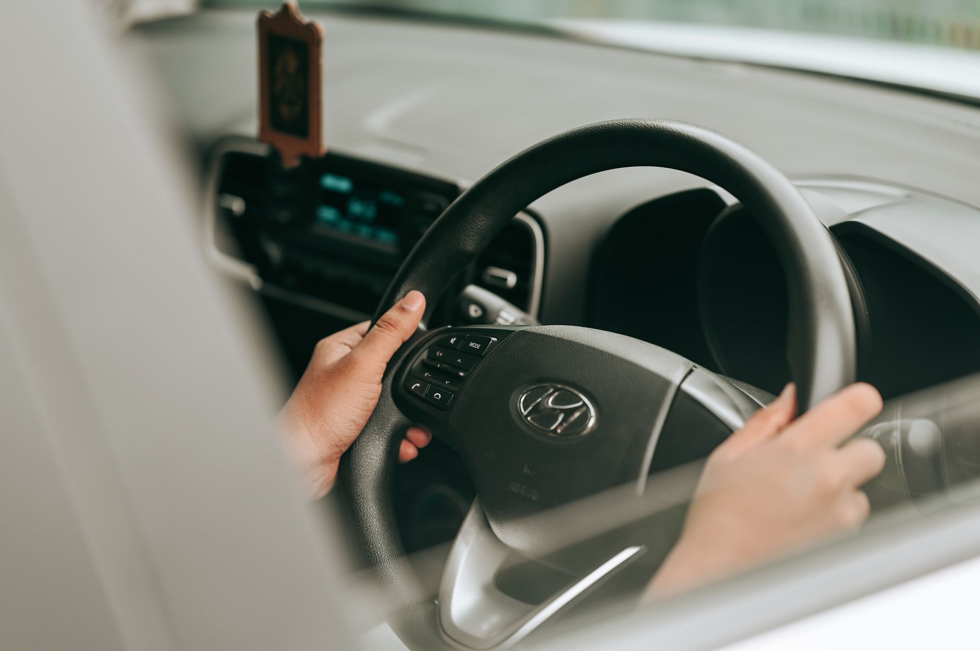 A close-up of hands holding a car's steering wheel while driving