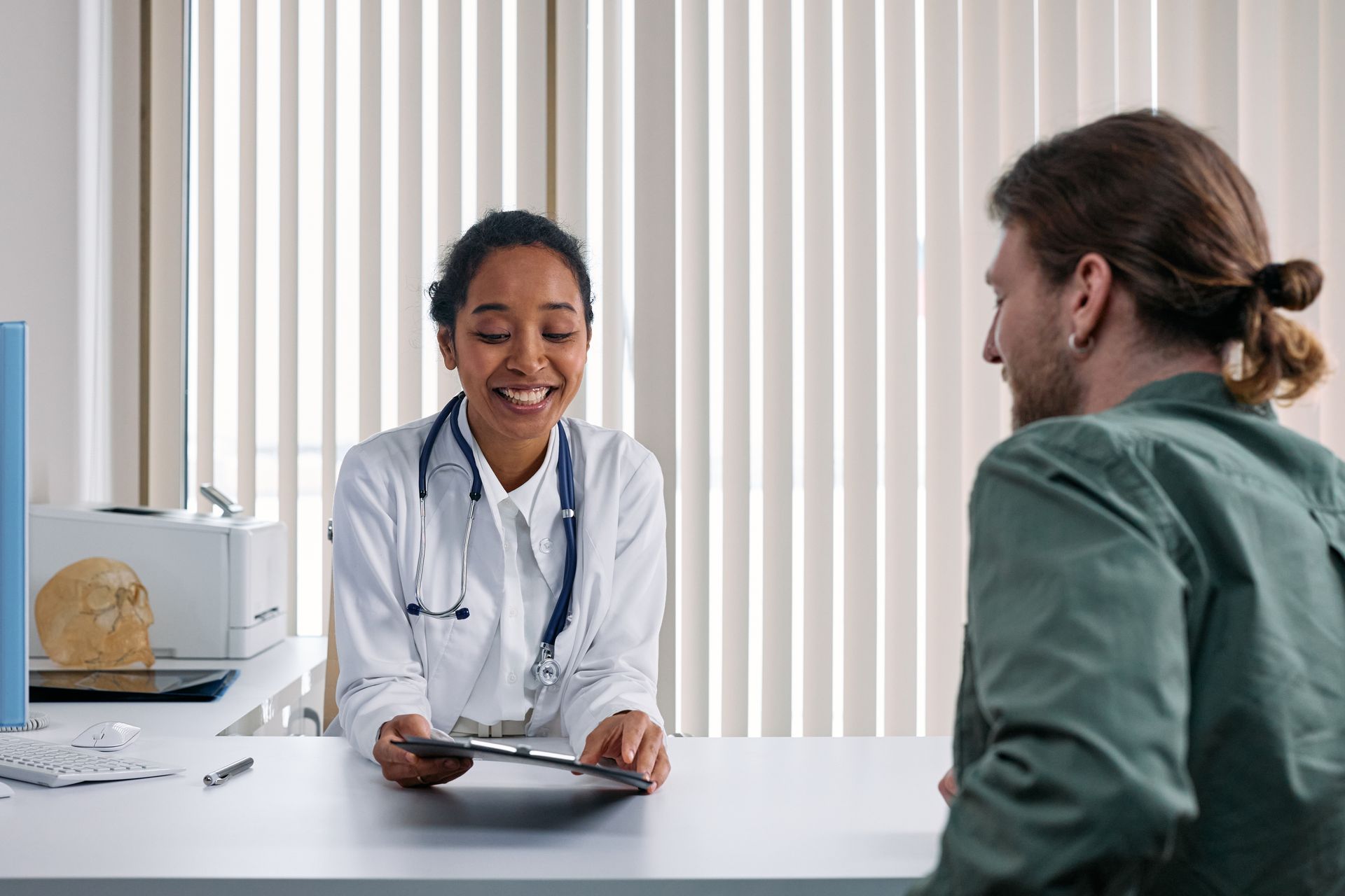 A doctor smiling while talking with a patient in a clinic office