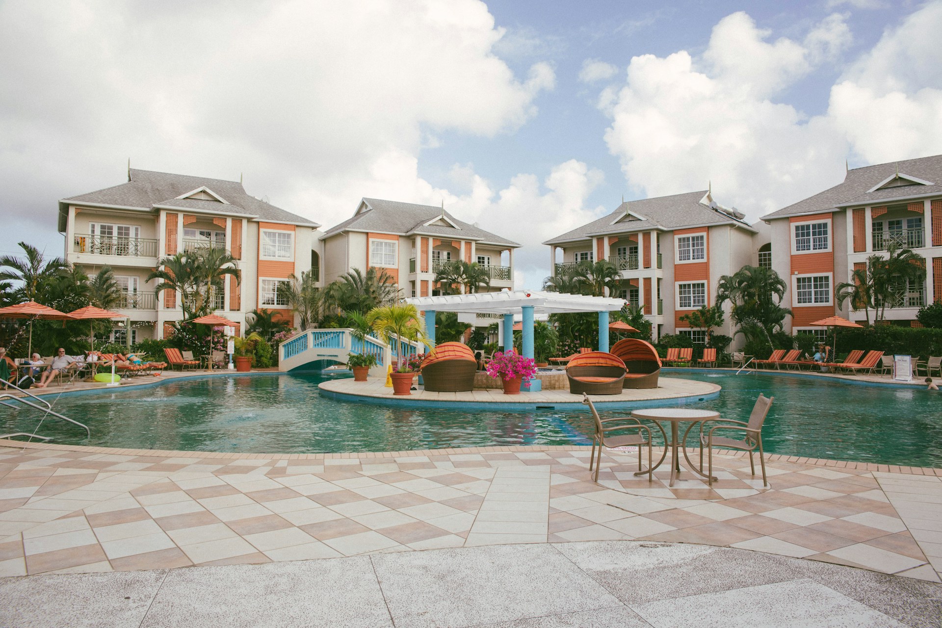 A resort-style condominium complex with a shared pool, landscaped gardens, and low-rise buildings