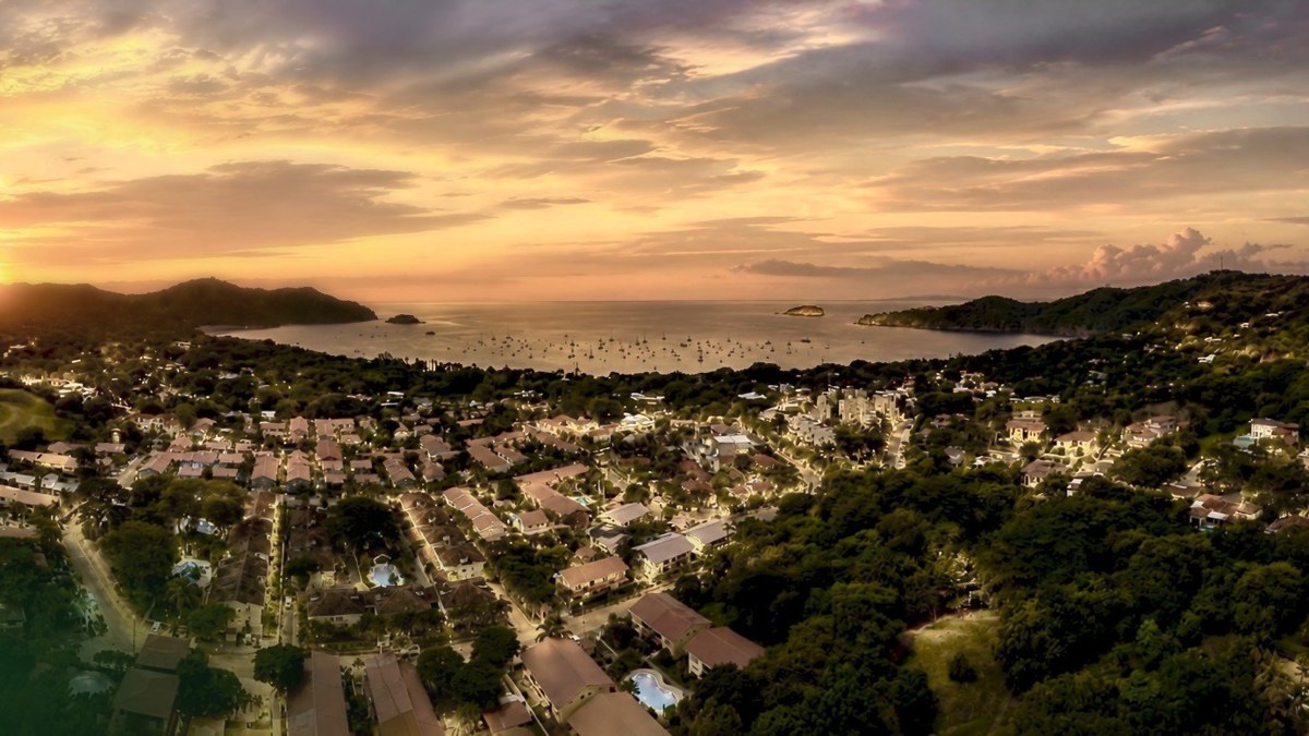 Vue aérienne d'une baie turquoise calme sur la côte du Guanacaste, avec des collines vertes en arrière-plan