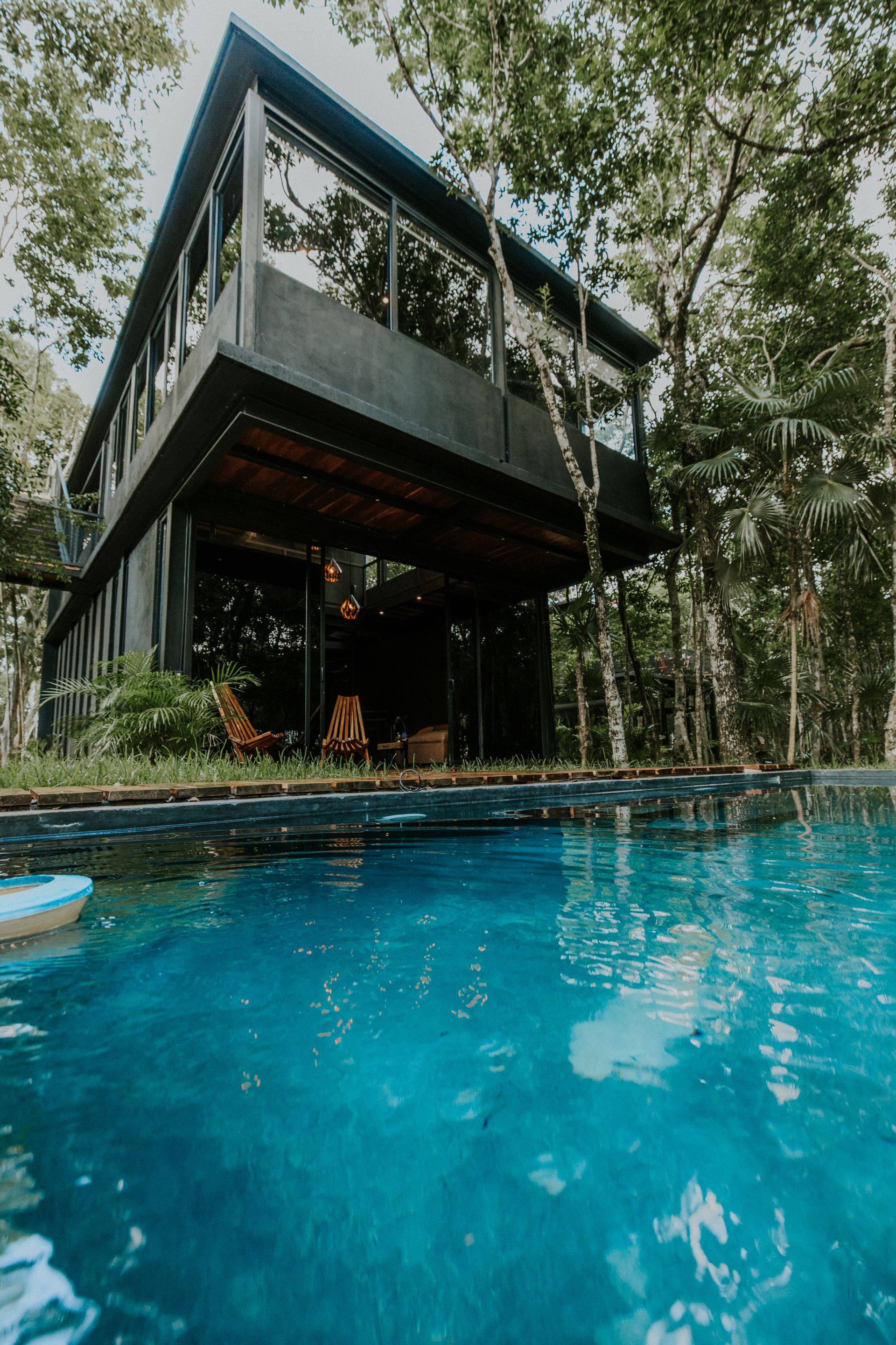 A modern tropical vacation home with a pool surrounded by lush forest