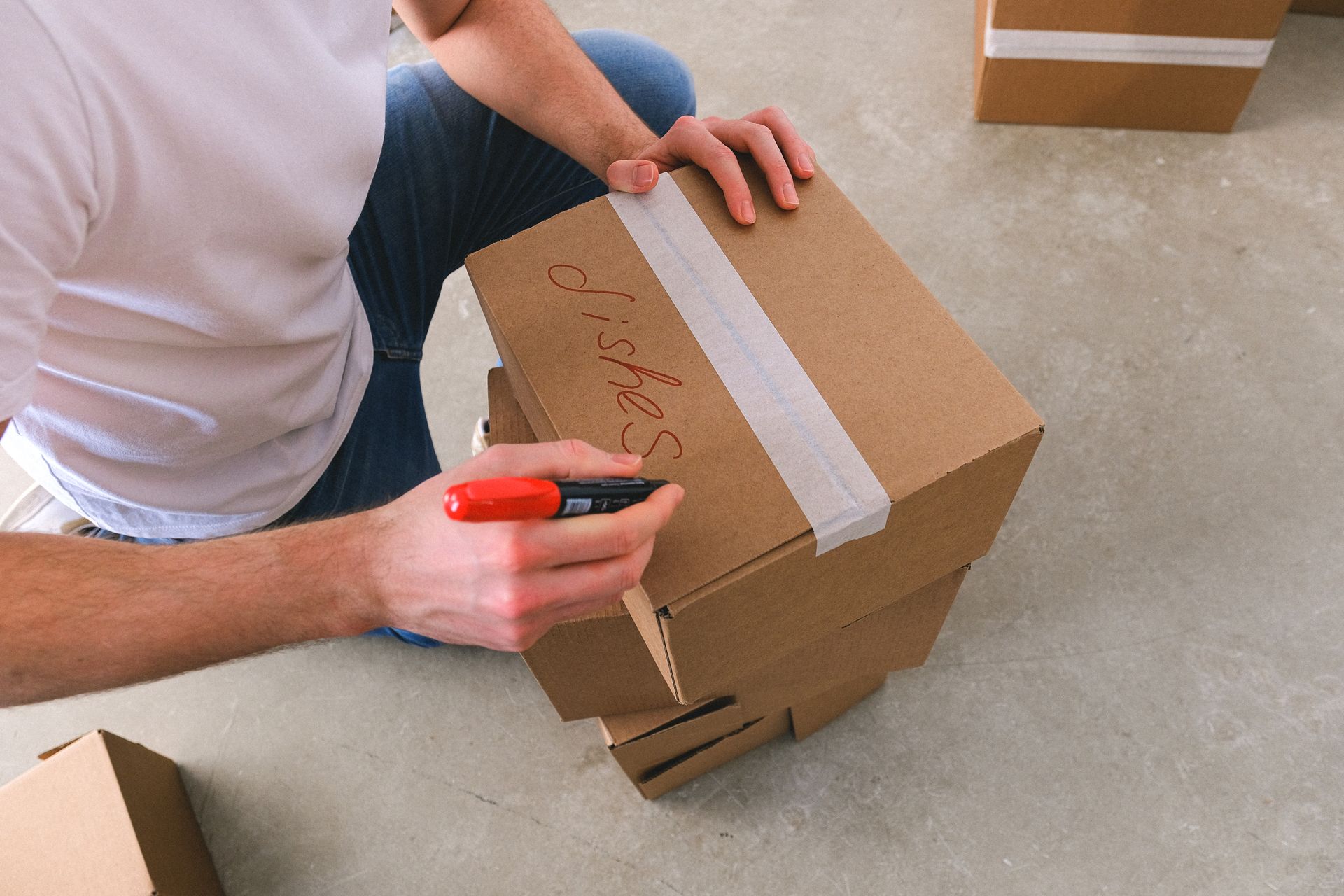 Une personne étiquetant une boîte de déménagement en carton avec un marqueur