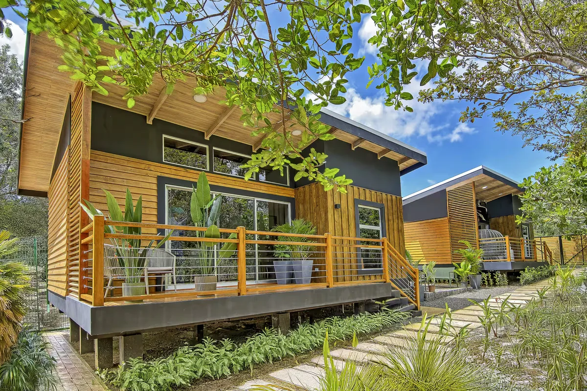 Modern elevated wood home surrounded by trees at Harmony Homes Curubandé