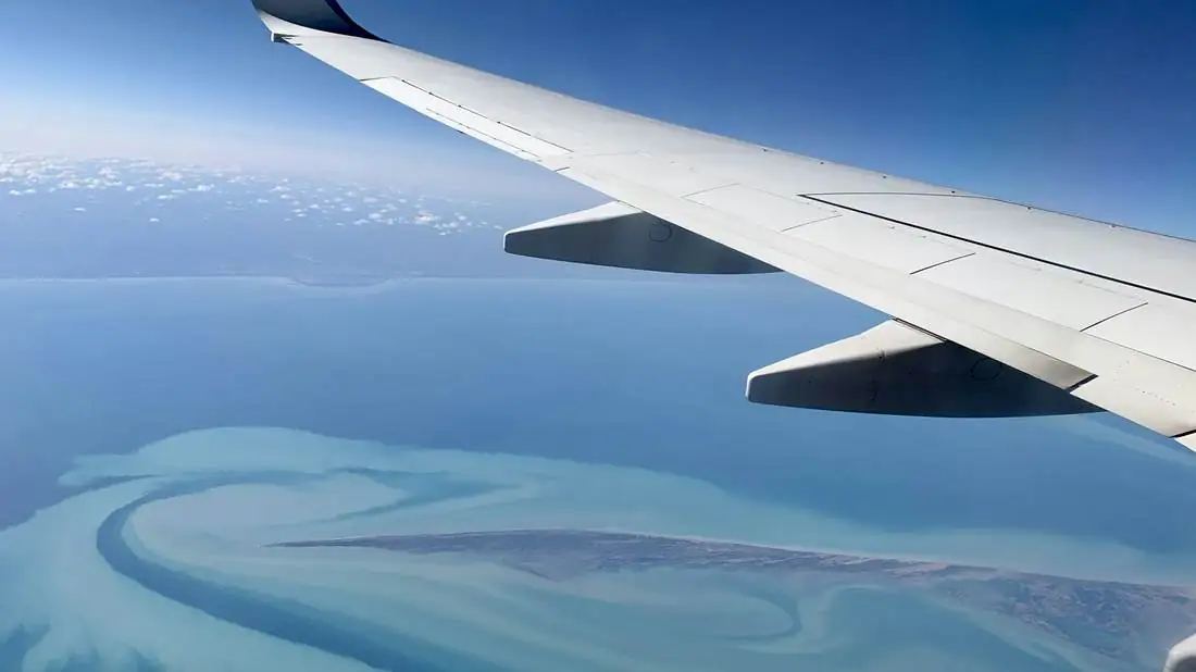 Airplane wing over the tropical coastline on approach to Guanacaste