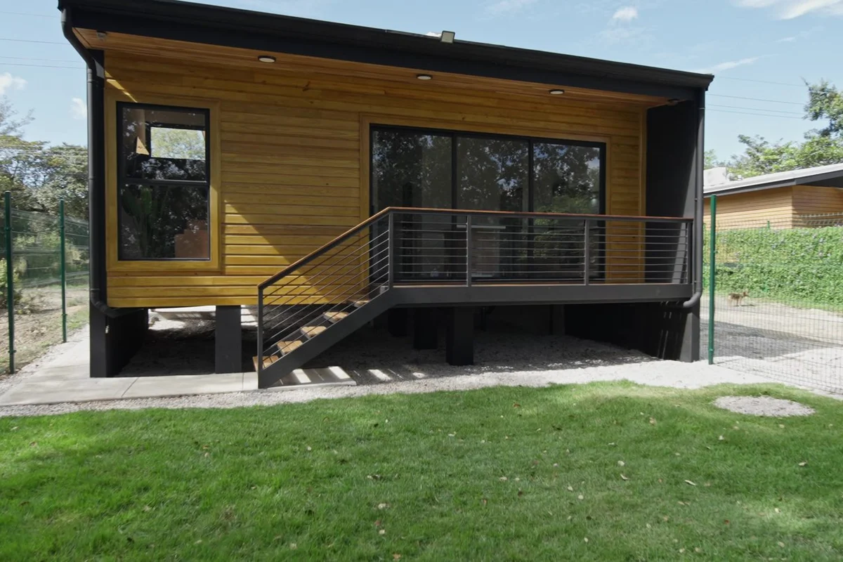Une maison Harmony avec revêtement en bois sur une structure d'acier surélevée, avec terrasse et escalier